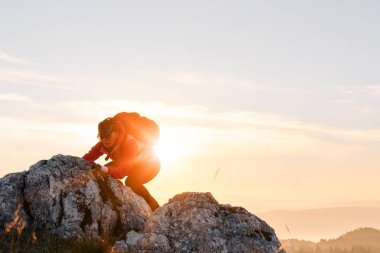 Güneşin doğuşunda Rocky Dağı 'na tırmanan kişi. Doğada azim ve mücadelenin sembolü olan altın gündoğumu sırasında kayalık dağa tırmanan kişi.