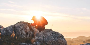 Güneşin doğuşunda Rocky Dağı 'na tırmanan kişi. Doğada azim ve mücadelenin sembolü olan altın gündoğumu sırasında kayalık dağa tırmanan kişi.