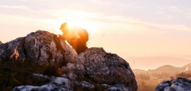 Güneşin doğuşunda Rocky Dağı 'na tırmanan kişi. Doğada azim ve mücadelenin sembolü olan altın gündoğumu sırasında kayalık dağa tırmanan kişi.