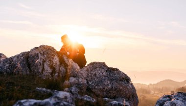 Güneşin doğuşunda Rocky Dağı 'na tırmanan kişi. Doğada azim ve mücadelenin sembolü olan altın gündoğumu sırasında kayalık dağa tırmanan kişi.
