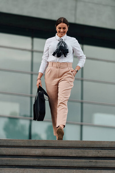 Стильная латиноамериканская деловая женщина уверенно ходит по оживленным улицам города с портфелем в руке и решительной улыбкой на лице. 