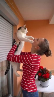 Balkonda kedisini öpen kadının portresi sevgi ve evcil hayvan sahibi ilişkisinin altını çiziyor.