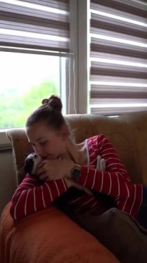 Genç bir kadın, siyah beyaz kedisine sarılmış, şefkat, bağ ve evcil hayvan sevgisini gösteriyor.