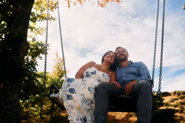 Dağlarda salıncakta sallanan bir çift, arka planda büyüleyici doğal manzarayla öpüşüyorlar. Seyahat, romantizm, yaşam tarzı ve macera temaları için mükemmel