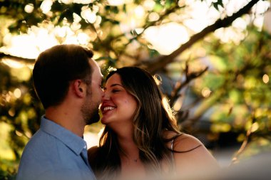 Genç çift, sıcak akşam güneşinde romantik bir öpücük paylaşıyor. Aşkı, samimiyeti ve mutluluğu simgeliyor. Yaşam tarzı, ilişki ve sevgililer günü temaları için mükemmel.