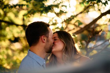 Genç çift, sıcak akşam güneşinde romantik bir öpücük paylaşıyor. Aşkı, samimiyeti ve mutluluğu simgeliyor. Yaşam tarzı, ilişki ve sevgililer günü temaları için mükemmel.