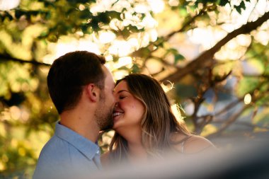 Genç çift, sıcak akşam güneşinde romantik bir öpücük paylaşıyor. Aşkı, samimiyeti ve mutluluğu simgeliyor. Yaşam tarzı, ilişki ve sevgililer günü temaları için mükemmel.