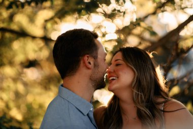 Genç çift, sıcak akşam güneşinde romantik bir öpücük paylaşıyor. Aşkı, samimiyeti ve mutluluğu simgeliyor. Yaşam tarzı, ilişki ve sevgililer günü temaları için mükemmel.