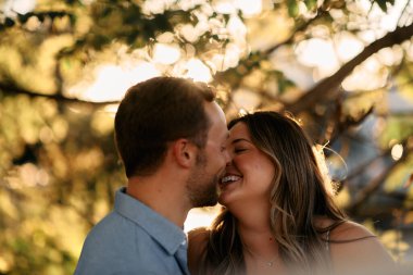 Genç çift, sıcak akşam güneşinde romantik bir öpücük paylaşıyor. Aşkı, samimiyeti ve mutluluğu simgeliyor. Yaşam tarzı, ilişki ve sevgililer günü temaları için mükemmel.