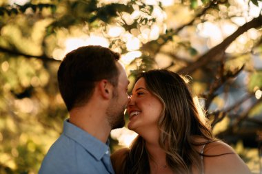 Genç çift, sıcak akşam güneşinde romantik bir öpücük paylaşıyor. Aşkı, samimiyeti ve mutluluğu simgeliyor. Yaşam tarzı, ilişki ve sevgililer günü temaları için mükemmel.