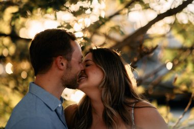 Genç çift, sıcak akşam güneşinde romantik bir öpücük paylaşıyor. Aşkı, samimiyeti ve mutluluğu simgeliyor. Yaşam tarzı, ilişki ve sevgililer günü temaları için mükemmel.