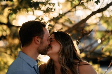 Genç çift, sıcak akşam güneşinde romantik bir öpücük paylaşıyor. Aşkı, samimiyeti ve mutluluğu simgeliyor. Yaşam tarzı, ilişki ve sevgililer günü temaları için mükemmel.