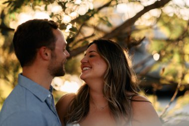 Genç çift, sıcak akşam güneşinde romantik bir öpücük paylaşıyor. Aşkı, samimiyeti ve mutluluğu simgeliyor. Yaşam tarzı, ilişki ve sevgililer günü temaları için mükemmel.