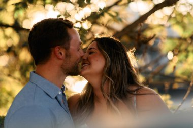 Genç çift, sıcak akşam güneşinde romantik bir öpücük paylaşıyor. Aşkı, samimiyeti ve mutluluğu simgeliyor. Yaşam tarzı, ilişki ve sevgililer günü temaları için mükemmel.