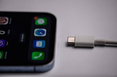 Gri arka planda C tipi şarj cihazıyla menü resmi olan yeni iPhone. Moldova,Hincesti 04.09.2023. Yüksek kalite fotoğraf