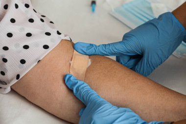 Ba virüsü aşısı olduktan sonra yaşlı bir kadına yapıştırıcı uygulayan bir hemşirenin yakın çekimi. 2.86. Yüksek kalite fotoğraf