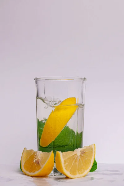Lemonade soda drink with fresh lemons. Refreshing cocktail with lemon, mint and ice on textured light background. Summer cold drinks concept. High quality photo