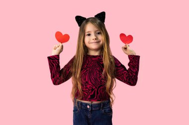 Elinde kağıt kalp şeklinde tebrik kartı tutan güzel bir kız. Pembe çocuk portresi. Kağıt kesiği, el yapımı bir hediye. Sevgililer Günü konsepti, tüm aşıkların bayramı. Yüksek kalite