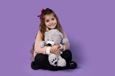 Küçük bir kız elinde oyuncak ayıyla otururken şaşırır ve onu göğsüne yakın tutar çünkü oyuncak onun en iyi ve en yakın arkadaşıdır. Oyuncak ayı çok yumuşak gri pelüş bir oyuncak. Yüksek