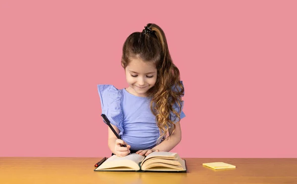 Picture of a little girl very happy to be at school, surprised how busy she was writing in her notebook, the little girl is very nicely dressed, she is dressed for school. High quality photo