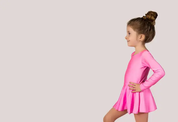 Pembe jimnastik elbisesi giymiş küçük bir kızın portresi diğer tarafa bakıyor. Metin ya da Sancak kopyalamak için boşluk. Yüksek kalite fotoğraf