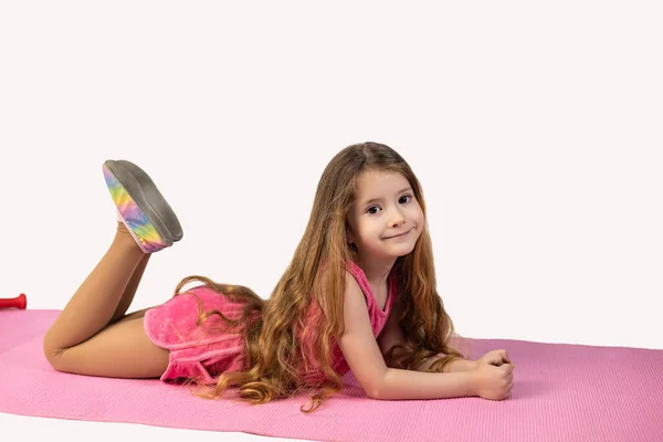 Jimnastikçi yoga minderine uzanmış kameraya bakıyor gülümsüyor, beyaz arka planda soyutlanmış. Yüksek kalite fotoğraf