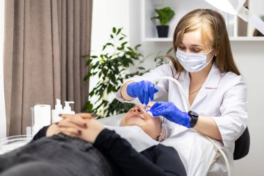 Kozmetik uzmanı yüzünde sivilce ve göz kenarındaki siyah noktalara karşı mikro dermabrüksiyon uygular. Güzellik salonunda kadın kozmetolojisi. Yüksek kalite fotoğraf