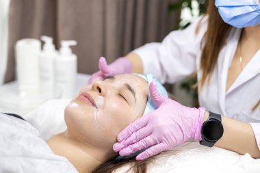 Kozmetik uzmanı, müşterinin cildini geliştirmek için yüz yüzeyine krem özü vitaminleri uyguluyor. Güzellik uzmanı hasta için güzellik tedavisi yapıyor. Sağlık, cilt bakımı, estetik tıp konsepti. Yüksek kalite