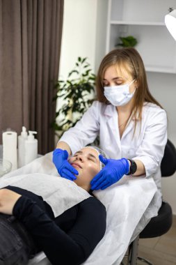Nitelikli bir kozmetolojistin, müşterileri maske uygulamasına hazırlayan yakın plan görüntüsü. Güzellik prosedürleri kavramı. Güzellik salonu. Yüz maskesi. Yüksek kalite fotoğraf