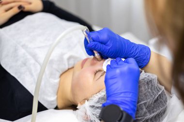 Kozmetoloji kliniğindeki güzel kadın hastalara hidro soyma işlemi yapan tıbbi eldivenler giyen profesyonel bir dermatolog. Yüz bakımını kapat. Yüksek kalite fotoğraf