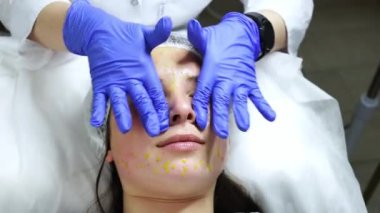 Biorepeel adında özel bir solüsyonlu yüz masajı, prosedür bir güzellik salonunda, uzman mavi eldiven giyiyor ve kız masaja çok hoş bir şekilde şaşırıyor. Yüksek kalite 4k