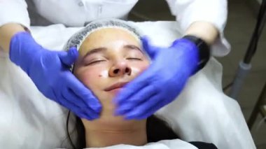 Biorepeel adında özel bir solüsyonlu yüz masajı, prosedür bir güzellik salonunda, uzman mavi eldiven giyiyor ve kız masaja çok hoş bir şekilde şaşırıyor. Yüksek kalite 4k