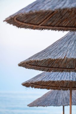 Plaj şemsiyesi, tente, samandan yapılmış tente ve açık mavi gökyüzüne karşı kamış, güneşli bir günde kumsalda. Yüksek kalite fotoğraf