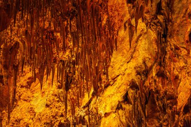 Alanya Turkey 'deki Damlatas mağarasındaki duvarda kahverengi taş mineral oluşumları, yakın plan. Sarkıtların ve dikitlerin doğal kahverengi-turuncu arka planı. Yüksek kalite fotoğraf