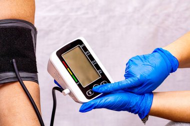 Kadın doktor klinikte yaşlı kadının kan basıncını ölçüyor ve sabah hasta geçmişini dolduruyor. Yüksek kalite fotoğraf