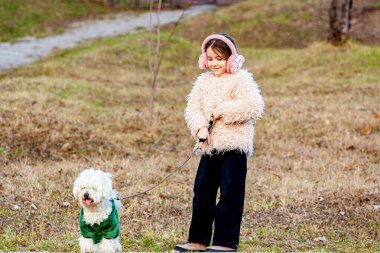 Birlikte olduğumuz için şanslıyız. Ailesi arkada yürürken köpekle koşan ve gülümseyen sevimli küçük bir kız. Yüksek kalite fotoğraf