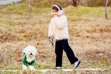Hayvan ve insanın güzel dostluğunun ön görüntüsü. Şirin küçük kız güneşli bir günde köpeğiyle dışarıda yürüyüşe çıkıyor. Yüksek kalite fotoğraf