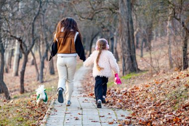 Aile günü, anneler günü. Güzel, gülümseyen genç bir anne ve küçük bir kız çocuğu bahçede mutlu bir evcil köpeğe sarılıyorlar. Anne ve kız çocuğu yaz tatilinde dışarıda evcil hayvanlarla eğleniyorlar. Yüksek