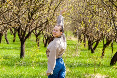 Bahar arka planında parlak ve güzel bir güneş gören bir resim kot pantolonlu güzel bir kız sorunlardan kurtulup rahatlıyor. Doğa, bir insanın hayatı ve sağlığı için bir ilaçtır. Koruruz.