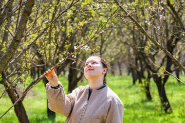 Baharda çiçek açmış bahçede gülümseyen genç bir kadının portresi. Badem çiçekleri çiçek açar. Gelin gibi beyaz giyinmiş bir kız. Yüksek kalite fotoğraf