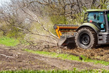 Orman temizliği konusunda uzmanlaşmış bir traktörün resmi tüm ağaçları ve çalıları yok etme sürecinde. Ormanların tahrip edilmesini durdurun. Doğayı yok eden büyük bir traktörün resmi. Yüksek kalite