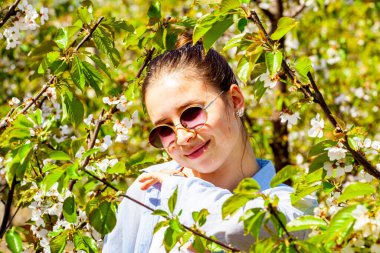 Genç bir bayan, kiraz çiçekleriyle dolu dalların arasında çok güzel bir portre görünce şaşırır. Ağaçlar beyaz çiçeklerle dolu ve çok hoş bir kokusu var. Küçük kız ise...