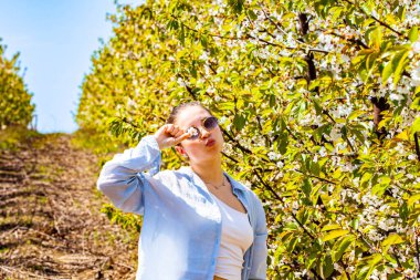 Özel ve güzel bir bayanın çok güzel bir portresi. Çiçekleri olan kiraz bahçesine ve çekici bir kokuya hayran kaldı. Parlak ve sıcak bir dönem. Doğa bize bu sahneyi sunar.