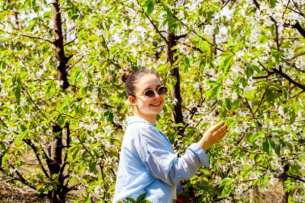 Kiraz bahçesindeyken çok güzel bir genç bayanın fotoğrafı ve çok güzel gülümsüyor. Küçük kız yakalı mavi gömlekli. Yüksek kalite fotoğraf