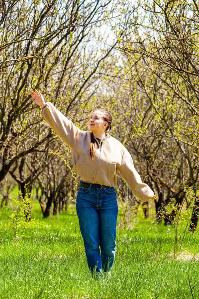 Çok güzel ve çekici bir kız doğanın bağrında yürürken ve gezegenimizin güzelliğine hayran kalırken bir badem bahçesi resmi. O mutlu ve bu yürüyüş onun için rahatlatıcı. Yüksek kalite