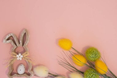 Trendy Easter image made with Bunny rabbit and yellow and green flowes  on pastel pink background. Minimal Easter concept.Flat lay with copy space.