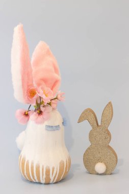 Funny Easter bunny, made of pumpkin,covered with white paint and added fancy lushes, ears,flowers.Golden bunny.  Pastel background. Creative concept with copy space.