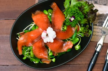 Healthy food meal cooked Fresh Salmon Salad served with Cucumber Roe and Lettuce bean sprouts Tomato garnished with salali and sesame oil sauce decorated with flowers