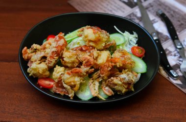 Fresh tuna salad served with sunflower sprouts and fresh organic lettuce in an elegant black plate placed on a wooden table and old newspapers.