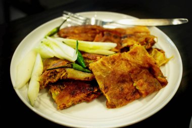 Martabak, Egg Martabak veya Egg Martabak. Yumurta, et ve baharatla doldurulmuş tuzlu hamur işleri. Martabak Telur tipik bir Endonezya sokak abur cuburudur. Tahta bir masada beyaz bir tabakta servis edildi..